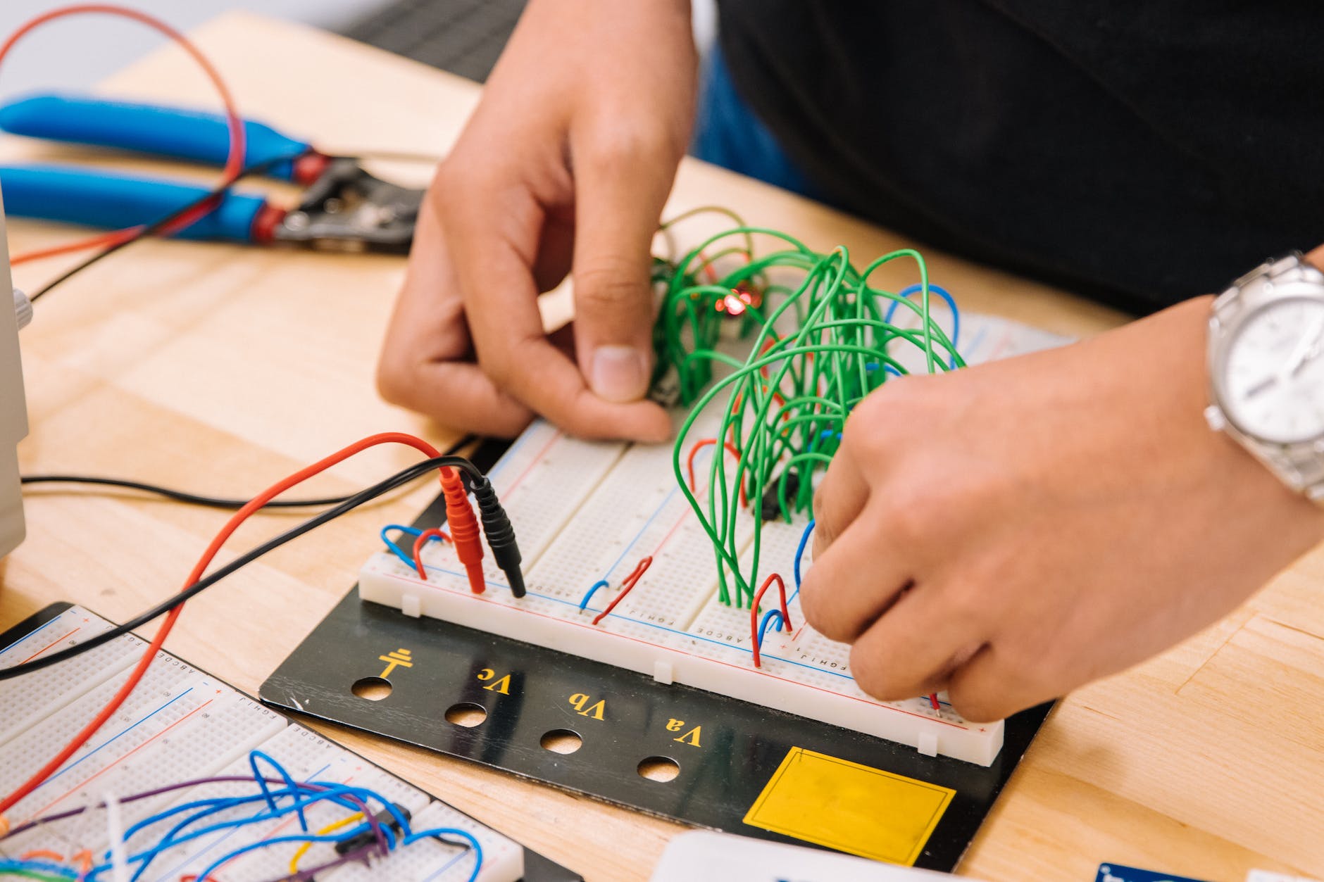 mains d'une personne tenant des fils sur une breadboard